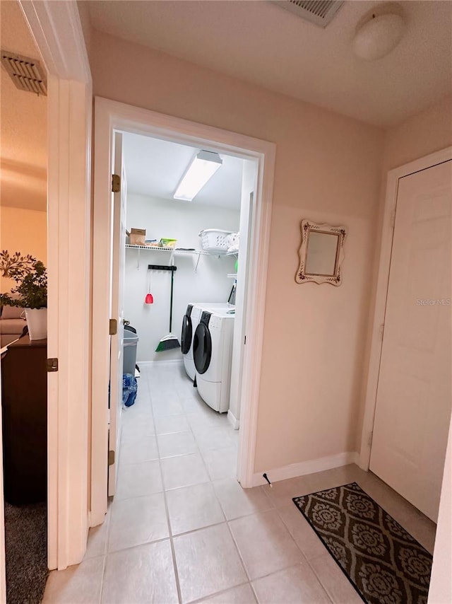 corridor with light tile flooring and washing machine and dryer