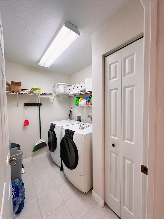 laundry area with a textured ceiling, washer hookup, independent washer and dryer, and light tile floors