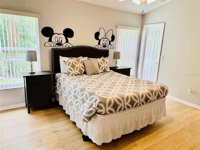 bedroom featuring vaulted ceiling, multiple windows, ceiling fan, and light wood-type flooring