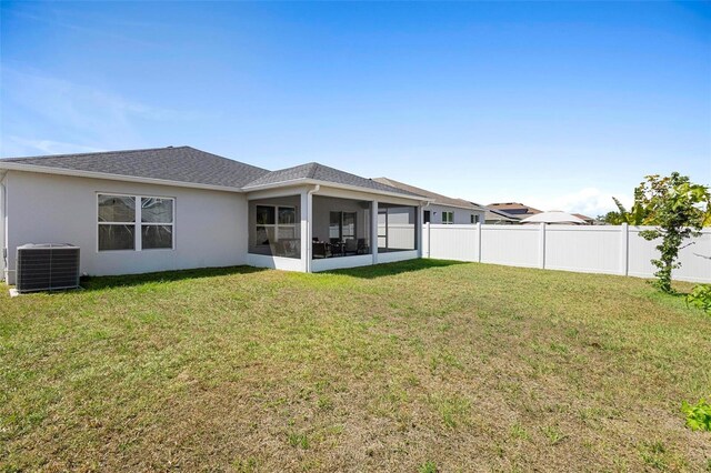 rear view of house with a sunroom, central AC unit, and a yard