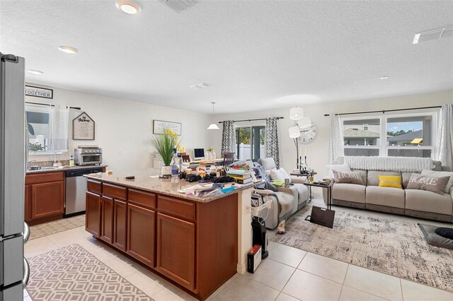 kitchen featuring a kitchen island, dishwasher, hanging light fixtures, light tile floors, and a textured ceiling