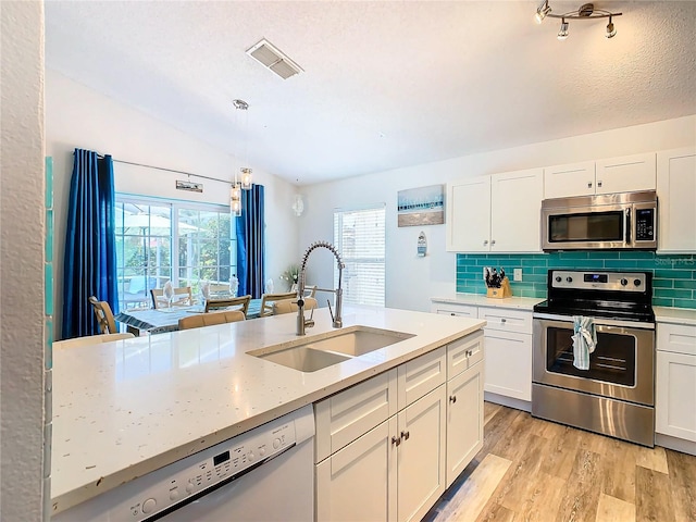 kitchen with white cabinetry, light hardwood / wood-style flooring, appliances with stainless steel finishes, pendant lighting, and sink