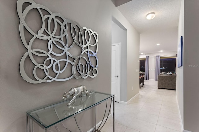 corridor featuring a textured ceiling and light tile floors