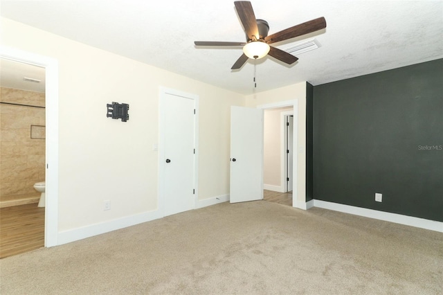 unfurnished bedroom featuring light carpet, ceiling fan, and ensuite bath