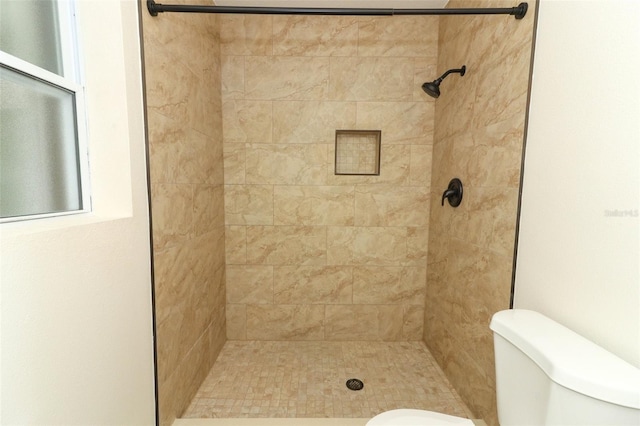 bathroom featuring tiled shower and toilet