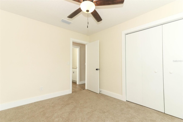 unfurnished bedroom featuring a closet, light colored carpet, and ceiling fan