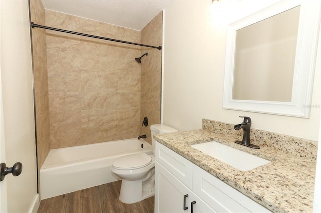 full bathroom with toilet, vanity, tiled shower / bath, and hardwood / wood-style floors