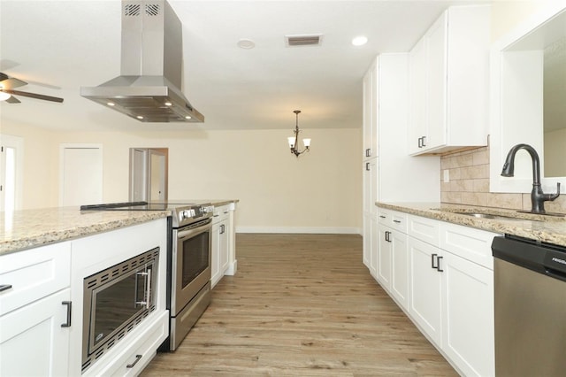 kitchen with stainless steel appliances, light stone counters, sink, ventilation hood, and white cabinetry