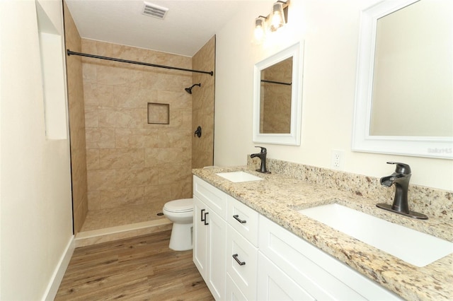 bathroom featuring tiled shower, wood-type flooring, toilet, and vanity