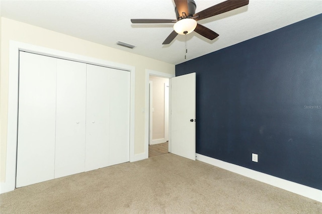 unfurnished bedroom with light colored carpet, ceiling fan, and a closet