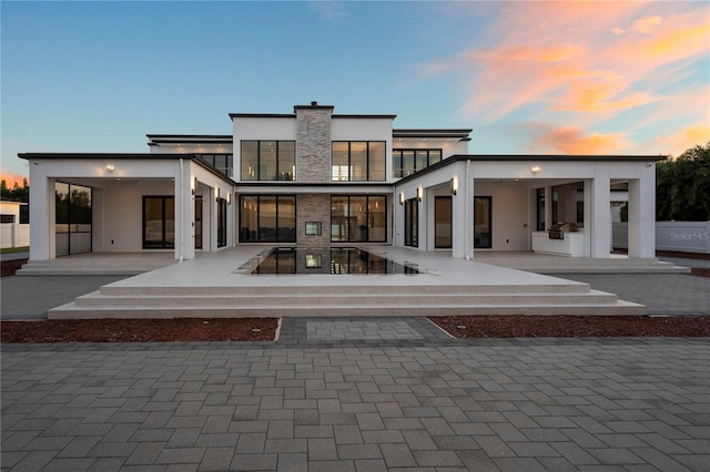 back house at dusk featuring a patio area and exterior kitchen