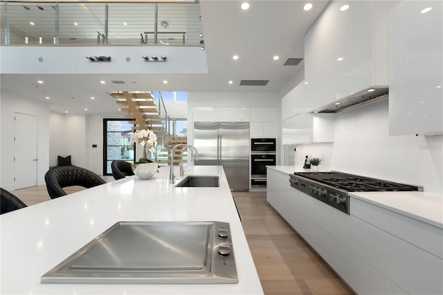 kitchen with white cabinets, stainless steel appliances, light hardwood / wood-style flooring, and sink