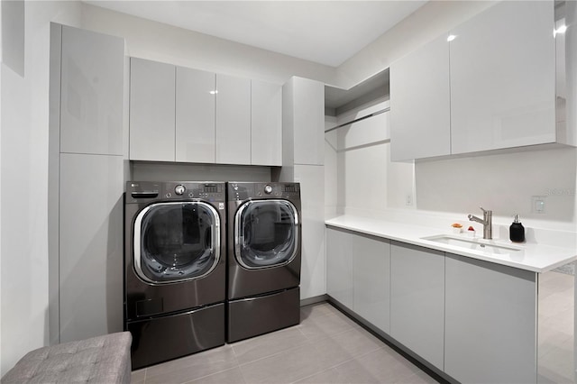 clothes washing area featuring washer and dryer, light tile patterned flooring, cabinets, and sink