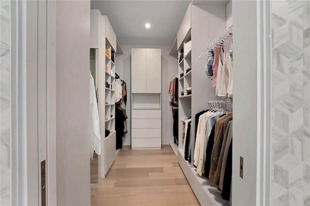 walk in closet with light hardwood / wood-style floors