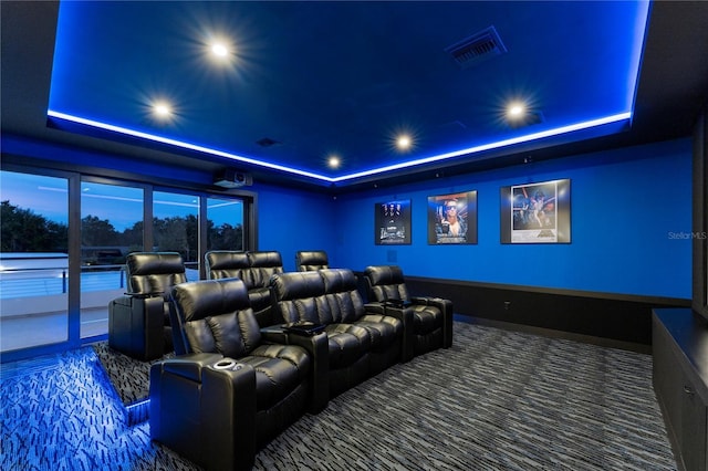 home theater room featuring carpet flooring and a raised ceiling