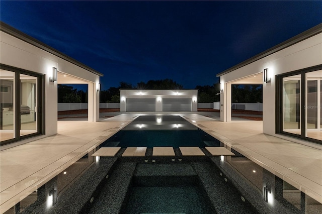 pool at twilight with a patio area and a jacuzzi