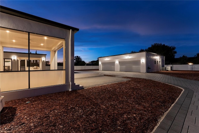 property exterior at dusk with an outdoor structure and a garage