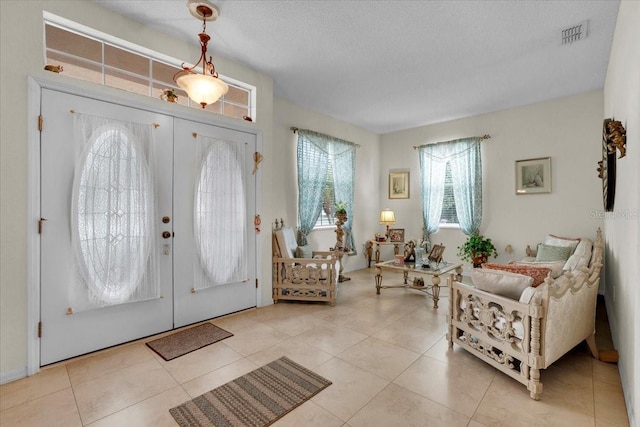 entryway with a textured ceiling, french doors, and light tile floors