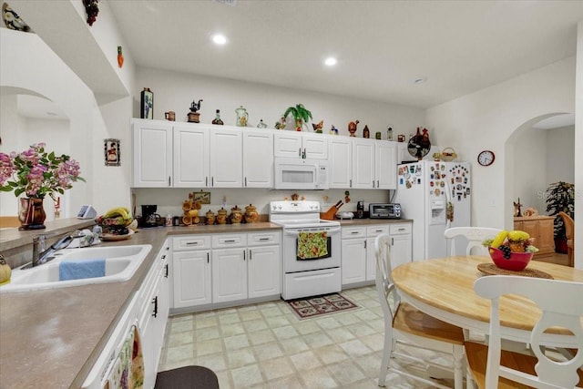 kitchen featuring sink, white cabinetry, white appliances, and light tile floors