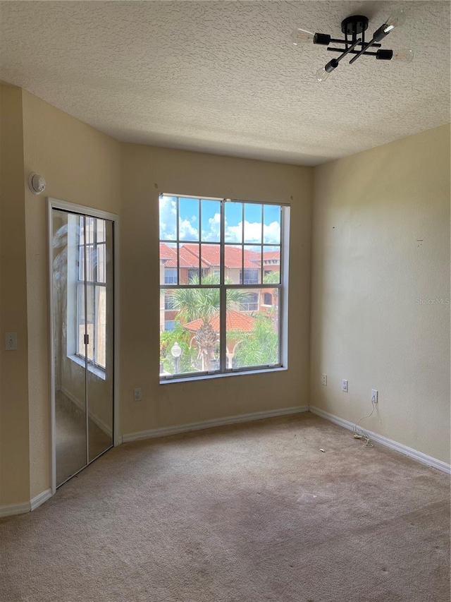 spare room with light carpet and a textured ceiling