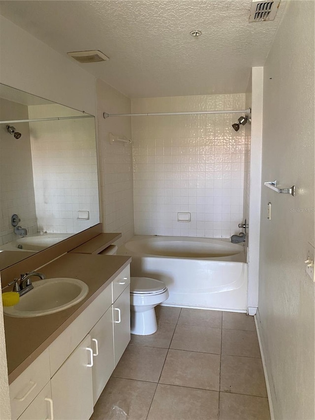 full bathroom with tile patterned flooring, vanity, a textured ceiling, tiled shower / bath, and toilet