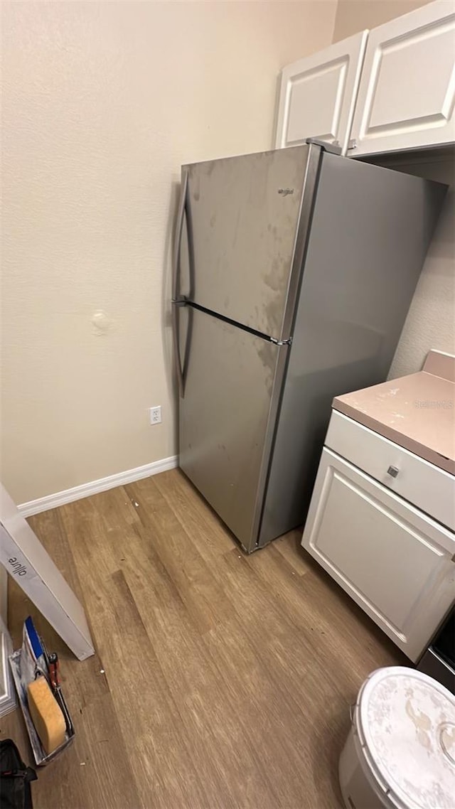 kitchen featuring white cabinetry, light hardwood / wood-style floors, and stainless steel refrigerator