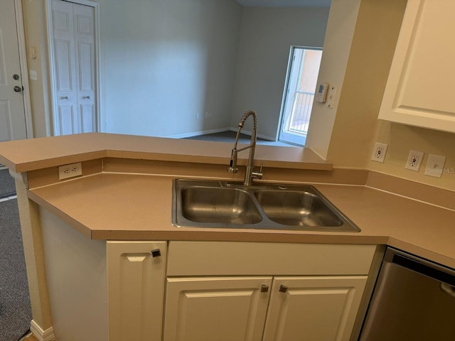 kitchen with white cabinetry, sink, stainless steel dishwasher, and kitchen peninsula