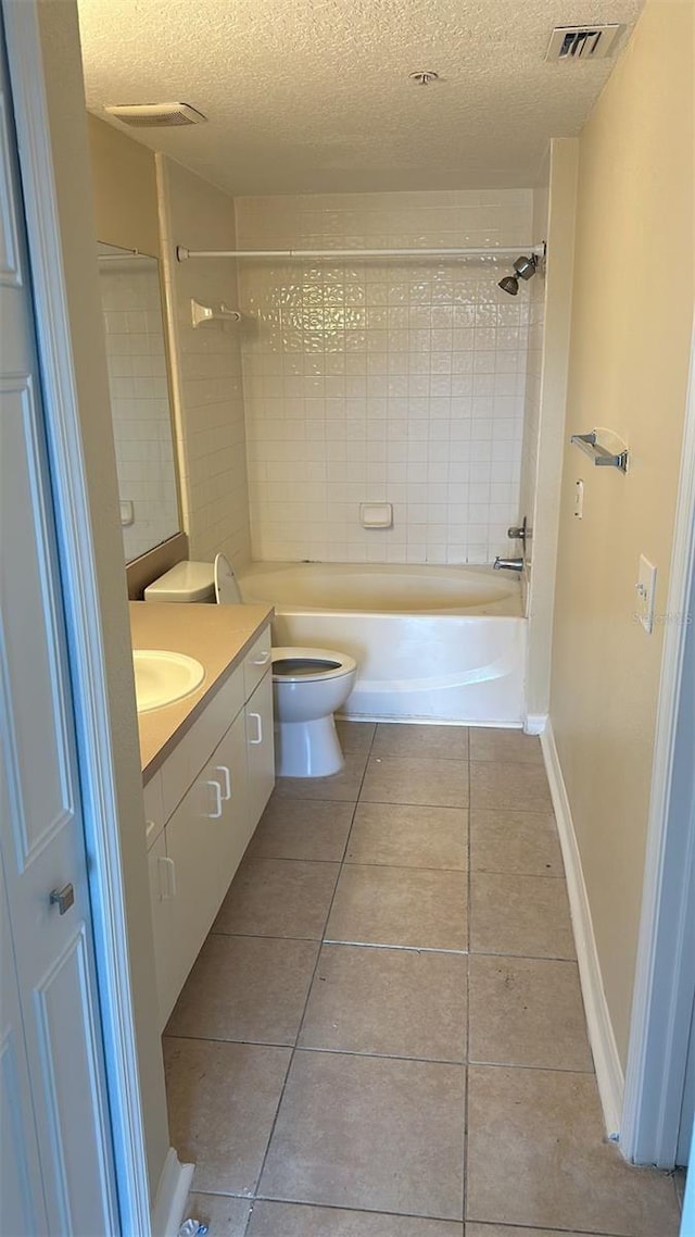 full bathroom with tile patterned flooring, vanity, a textured ceiling, toilet, and tiled shower / bath