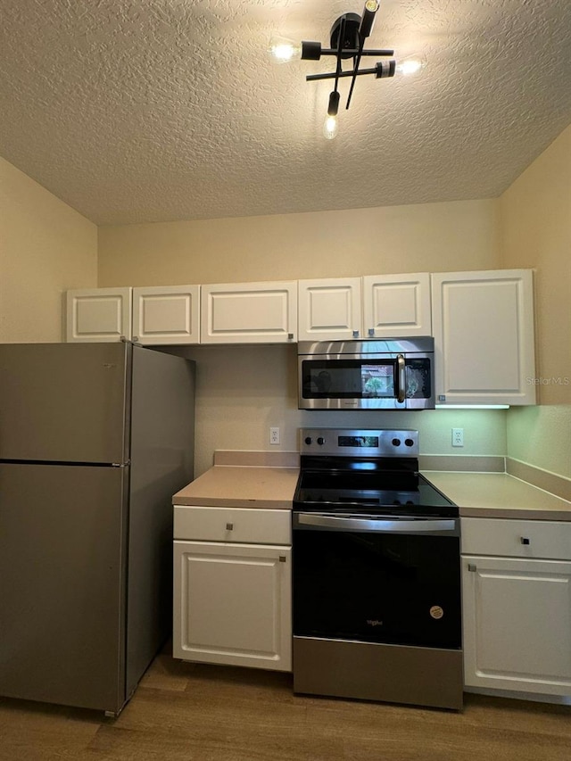 5500 Metrowest Blvd Unit 304, Orlando, FL 32811 - kitchen with stainless steel appliances, white cabinetry, light countertops, a textured ceiling, and dark wood finished floors
