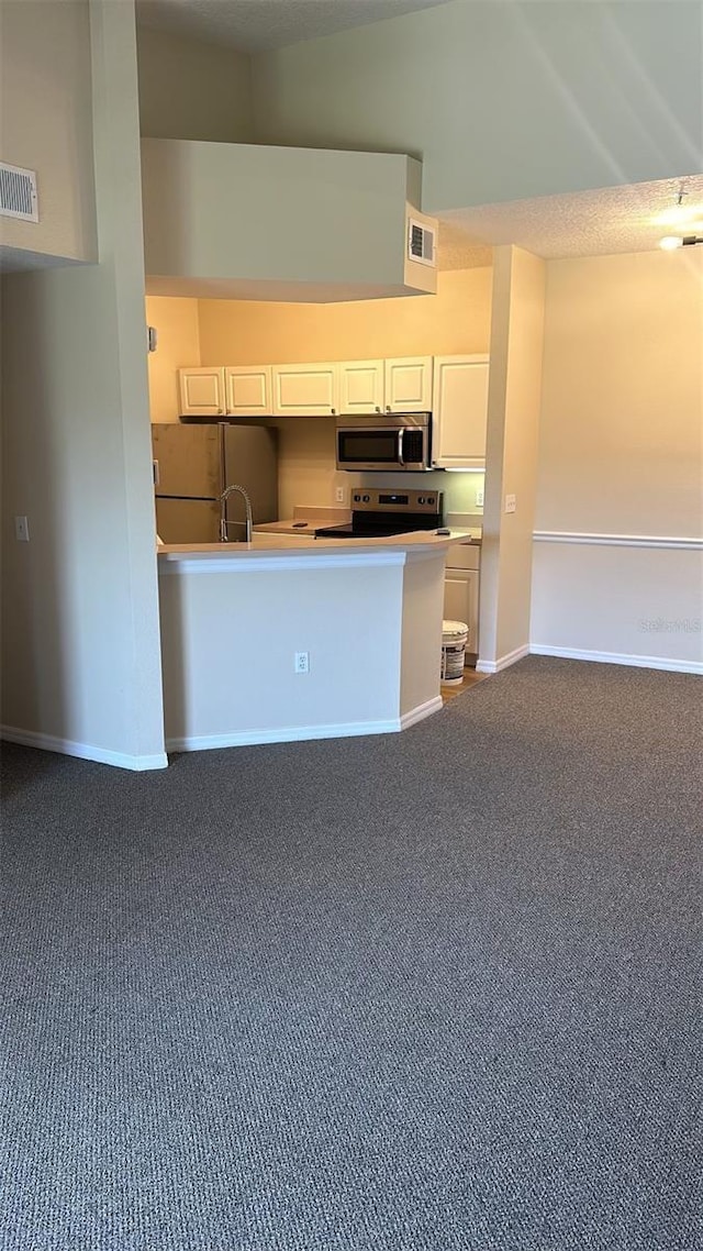 kitchen featuring white cabinetry, stainless steel appliances, and dark colored carpet