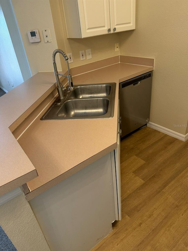 kitchen with light wood-type flooring, stainless steel dishwasher, sink, and white cabinets