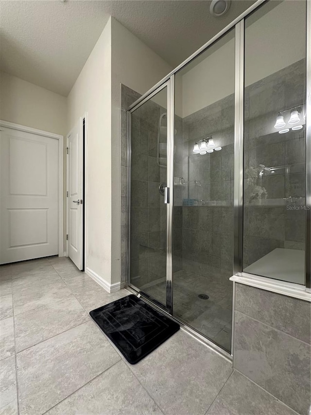 bathroom with tile flooring, walk in shower, and a textured ceiling