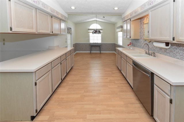 kitchen featuring lofted ceiling, light hardwood / wood-style flooring, stainless steel dishwasher, decorative light fixtures, and sink