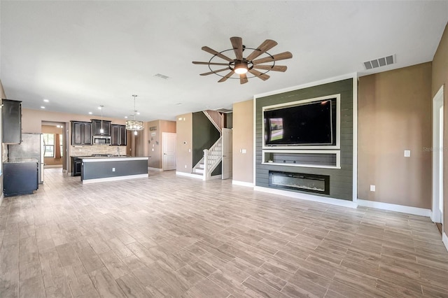 unfurnished living room featuring a large fireplace, light wood-type flooring, and visible vents