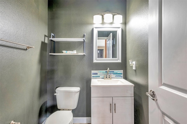 bathroom with a textured wall, vanity, and toilet