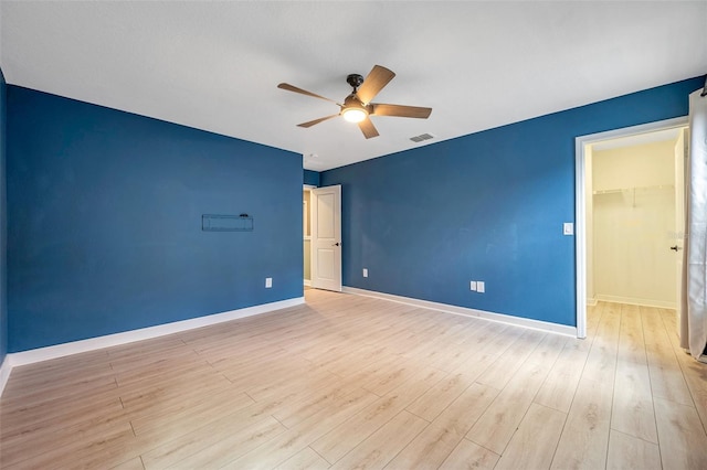 empty room featuring light wood-style floors, visible vents, baseboards, and a ceiling fan