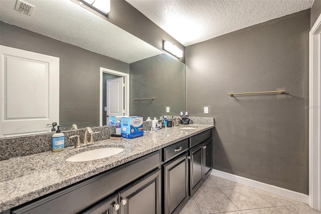 full bathroom featuring double vanity, visible vents, tile patterned flooring, a textured ceiling, and a sink