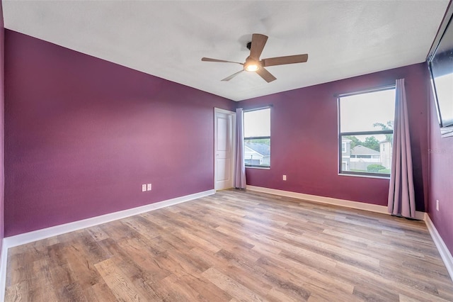 unfurnished room featuring a ceiling fan, light wood-type flooring, and baseboards