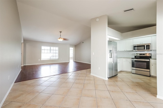 kitchen featuring light hardwood / wood-style floors, stainless steel appliances, white cabinets, decorative light fixtures, and tasteful backsplash