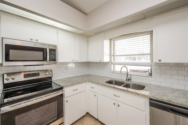 kitchen featuring tasteful backsplash, light tile flooring, sink, white cabinetry, and appliances with stainless steel finishes