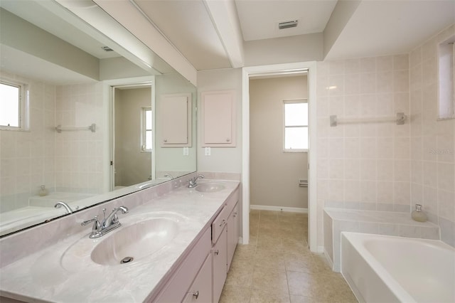 bathroom with dual bowl vanity, tile flooring, a bath to relax in, and a wealth of natural light