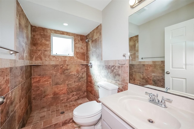 bathroom with tile walls, tiled shower, toilet, and large vanity