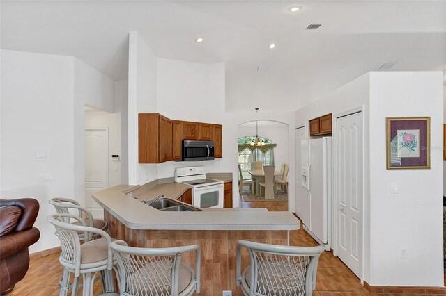 kitchen with sink, white appliances, kitchen peninsula, and a breakfast bar