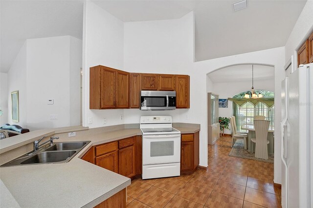 kitchen with sink, white appliances, light tile patterned floors, a notable chandelier, and decorative light fixtures