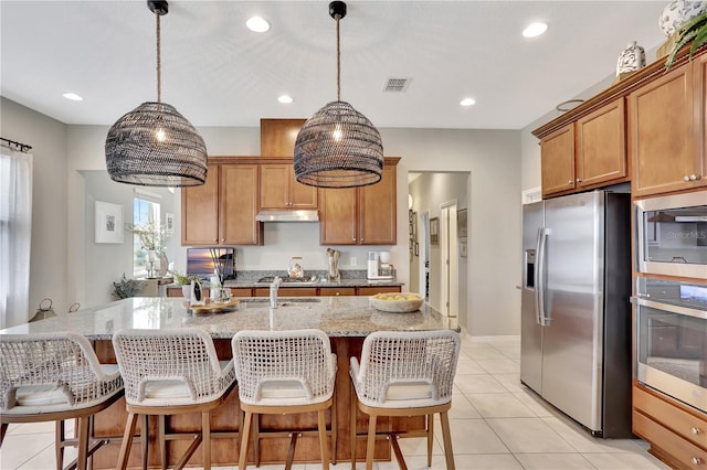 kitchen featuring stainless steel appliances, a center island with sink, light tile floors, and pendant lighting