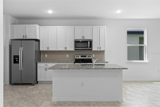 kitchen featuring an island with sink, light stone counters, appliances with stainless steel finishes, and white cabinets