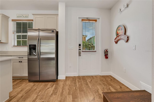 kitchen with light hardwood / wood-style floors and stainless steel fridge with ice dispenser