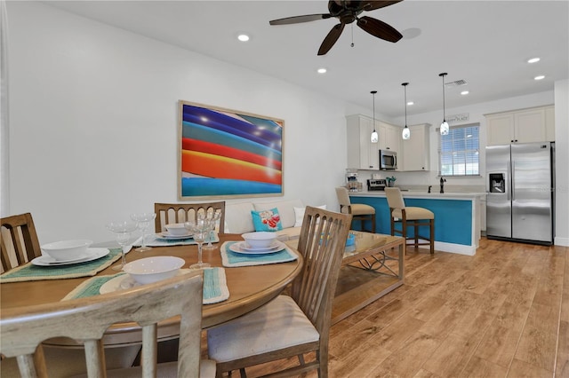 dining area featuring ceiling fan, light wood-type flooring, and sink