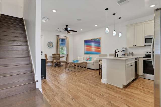 kitchen featuring ceiling fan, light hardwood / wood-style flooring, stainless steel appliances, hanging light fixtures, and sink