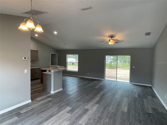 unfurnished living room with plenty of natural light, dark hardwood / wood-style floors, ceiling fan with notable chandelier, and vaulted ceiling